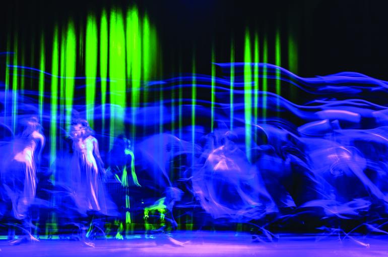 Abstract purple, green, and black image of people dancing