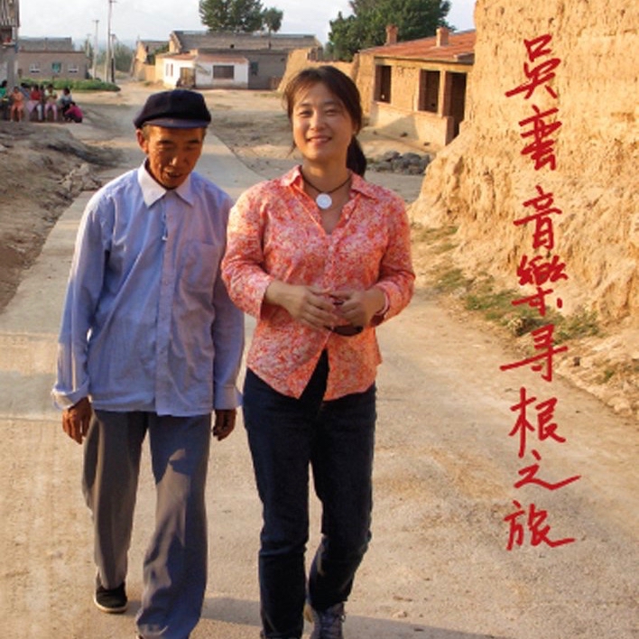 Wu Man walks with an elderly Chinese man down a dirt road