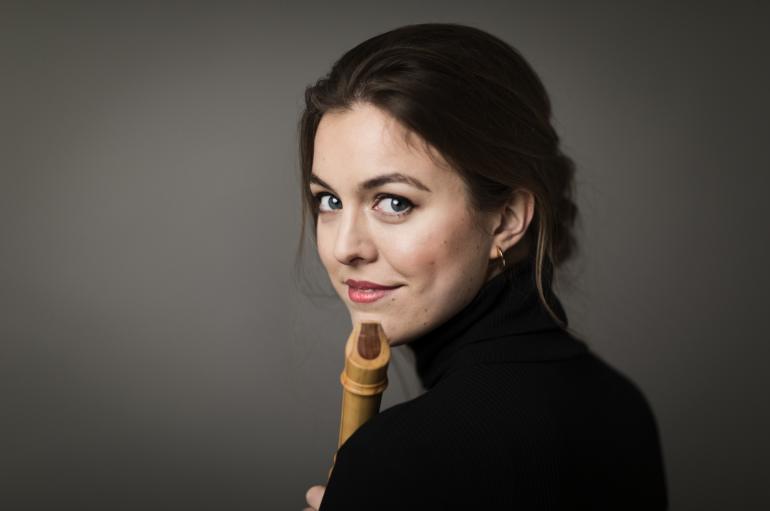 Tabea Debus looking over her shoulder and holding a recorder