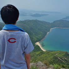A male student views the coastline off Hong Kong from atop a mountain.
