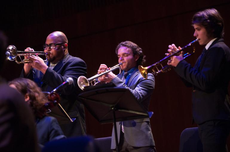 Three young men play trumpets