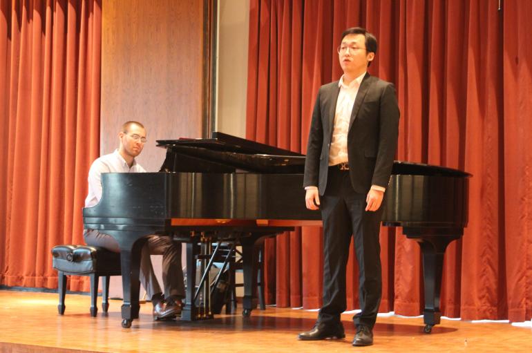 A young man performs on stage with piano in Fulton Recital Hall