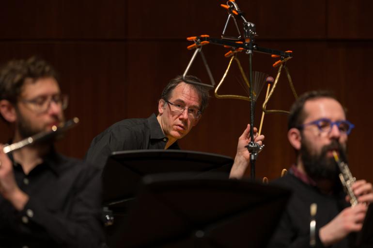 Closeup photo of three men, Tim Munro playing flute, Greg Beyer playing percussion, and Andrew Nogal playing oboe