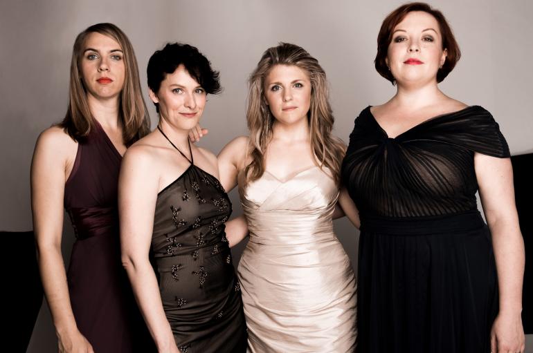 Quince vocal ensemble: 4 women standing next to each other wearing elegant gowns