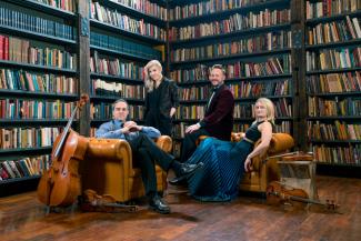 Spektral Quartet sitting in armchairs with instruments in a library